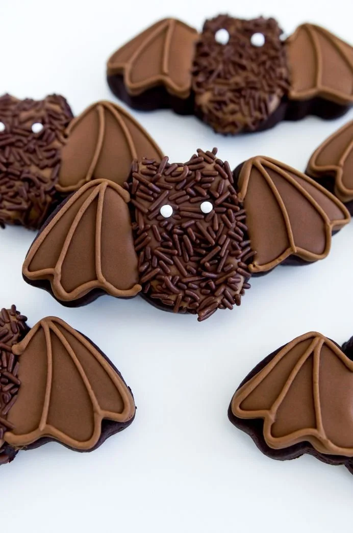 Plate of Halloween cookies shaped like ghosts, pumpkins, and spiders.