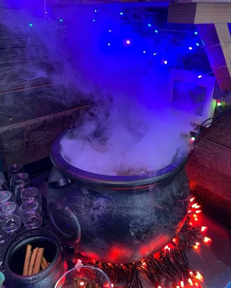 A spooky witchy batch cocktail served in a cauldron for Halloween.