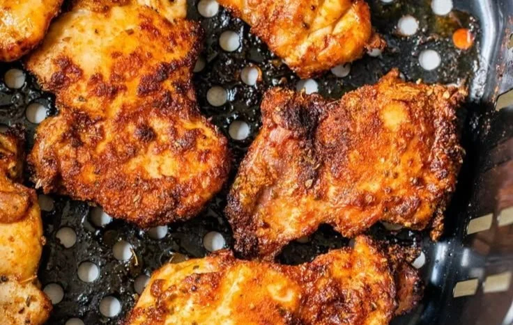 Crispy air fryer boneless chicken thighs served on a plate with herbs