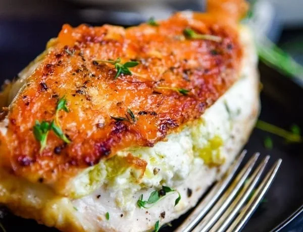 Goat cheese stuffed chicken breast plated with fresh herbs and vegetables
