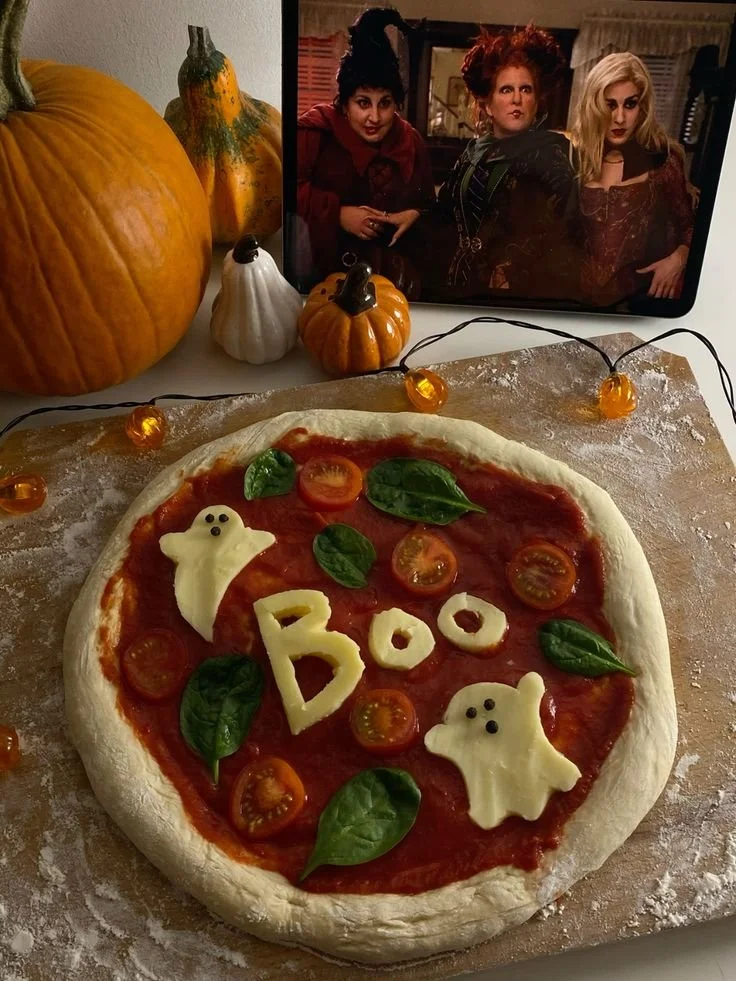 A spooky pizza adorned with Halloween-themed toppings and decorations.
